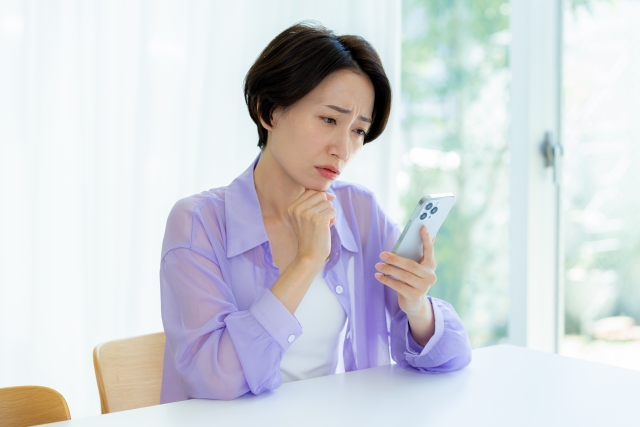 スマホをみて悩む女性