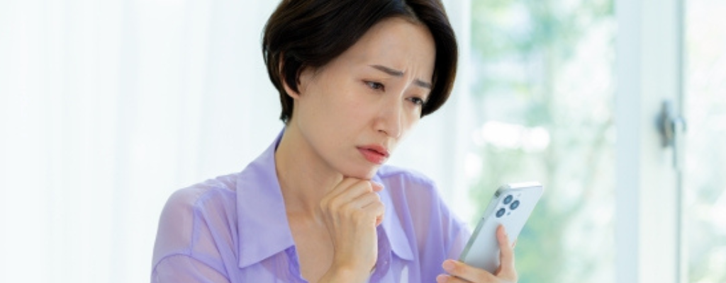 スマホをみて悩む女性