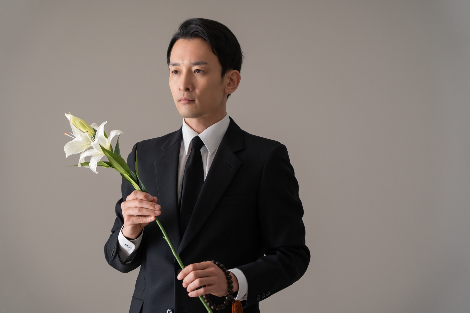 百合の花を持った喪服の男性