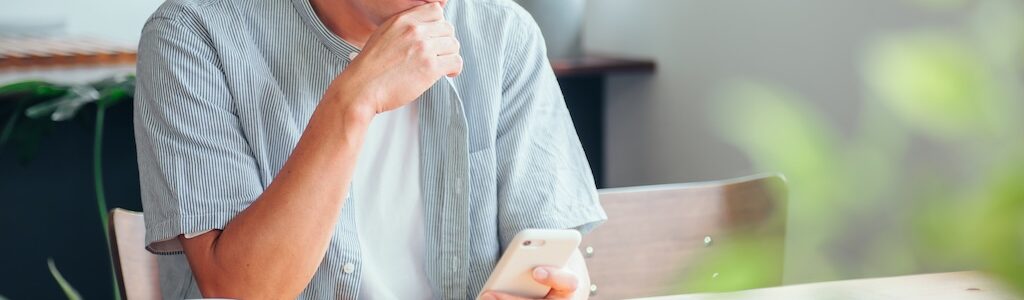 電話を手に悩む男性